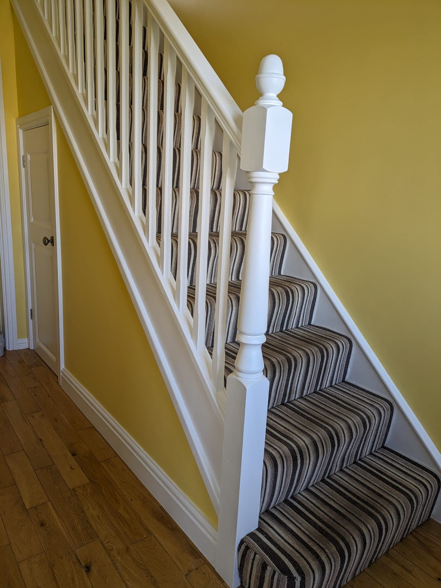 Hallway after — white spindles and saffron feature wall