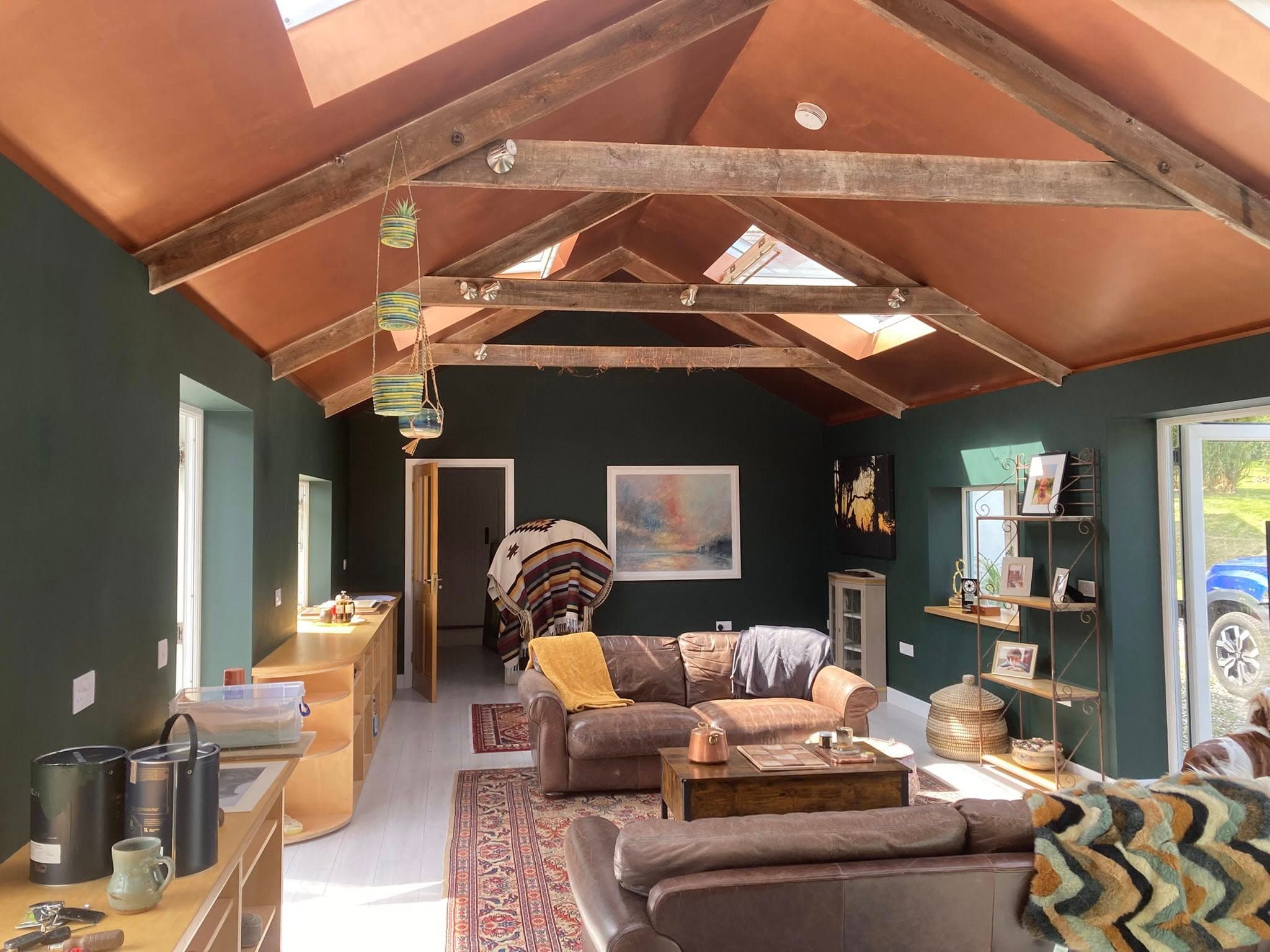 Sitting room after — deep green walls + warm terracotta vaulted ceiling